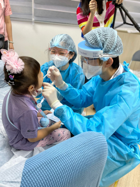 A dentist performs an oral examination on a child participant, collecting her dental plaque samples.